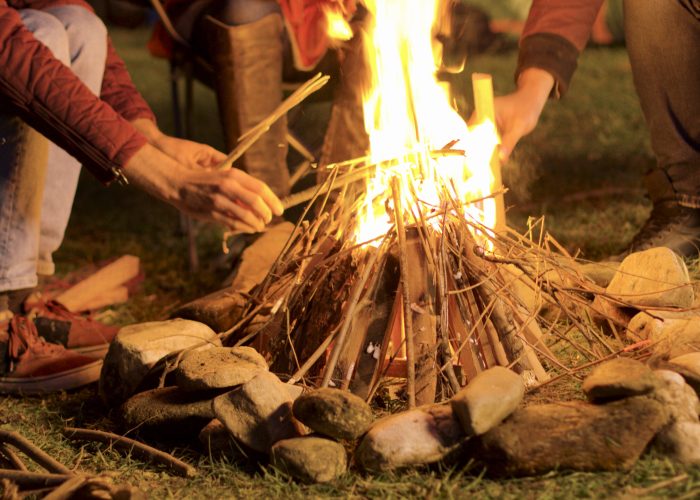Handheld footage of man making camp fire for his friends in a cold night.